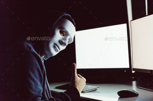 hacker giving thumbs up while using a computer with empty blank white screen in the dark room