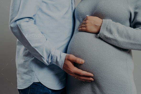 Smiling pregnant woman in headphones touching her belly. Pregnancy,  maternity, preparation and expectation concept Stock Photo