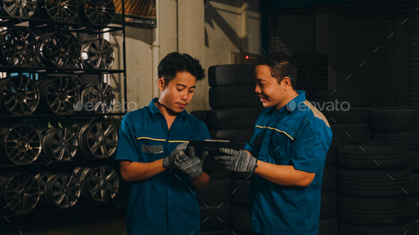 Two professional car mechanic using paperwork makes the oil and engine check to the car.