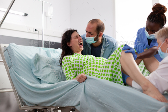 Young woman giving birth and pushing in hospital ward bed