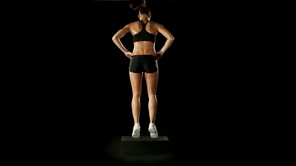 Young Athletic Woman Wearing Sporstwear is Exercising with Step Slow Motion Isolated on Black