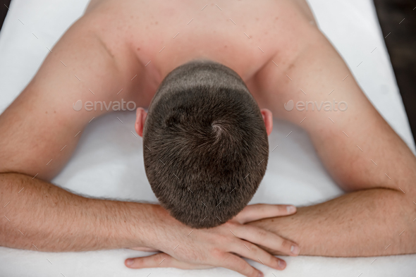 Female hands do a back massage to a man in the salon. Stock Photo by puhimec