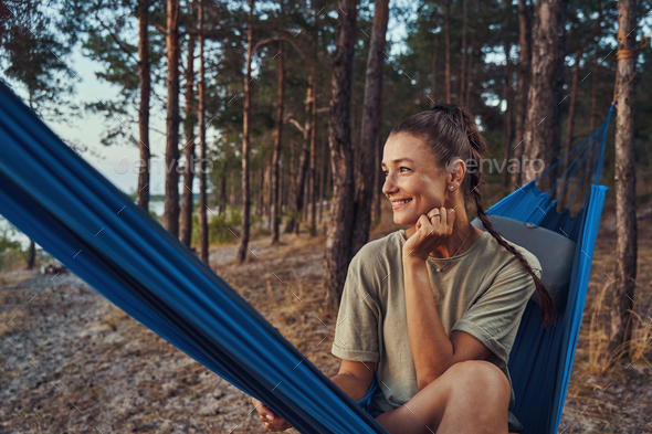 Cheerful female in the woods sitting on hammock