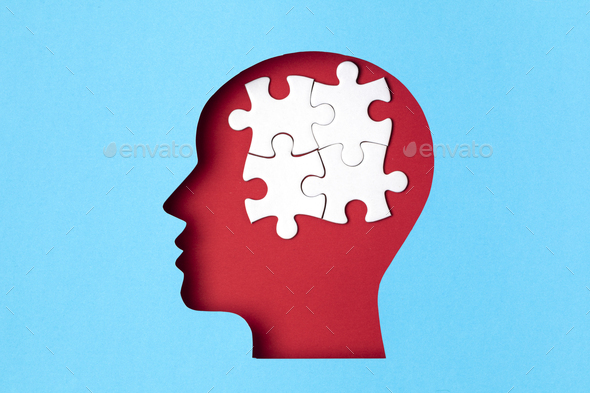 Papercut head with jigsaw puzzle pieces inside. Mental health problems, psychology, memory, logic