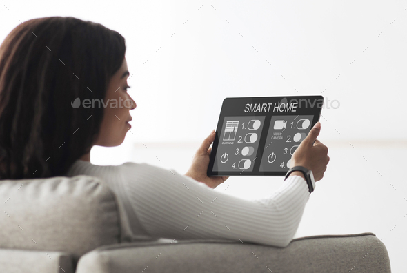 Smart home control concept. Black housewife using digital tablet