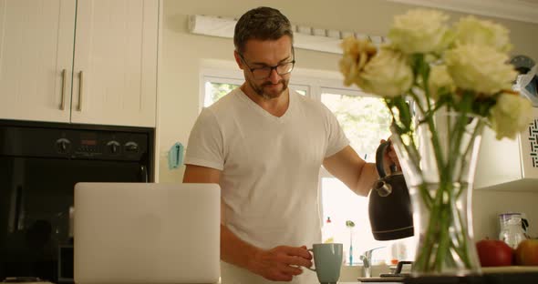 Man pouring water into coffee cup in kitchen  alt