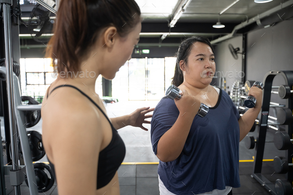 Chubby asian woman with personal trainer Stock Photo by pondsaksit