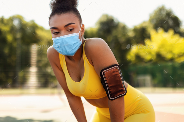 Woman wearing protective face mask resting after exercising