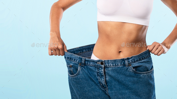Closeup Of Skinny Fit Woman Pulling Large Loose Jeans