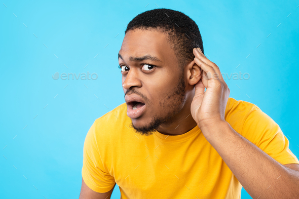 African American Guy Listening Holding Hand Near Ear, Blue Background