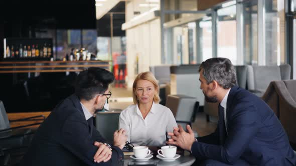Businesswoman Paying for Lunch with Smartphone During Meeting with Partners alt