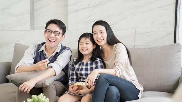 Happy asian family watching tv together on sofa in living room - Stock Photo - Images