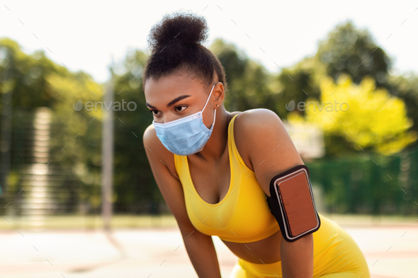 Woman wearing protective face mask resting after run