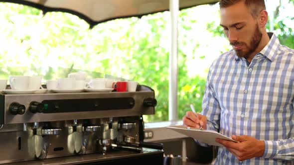 Male owner noting on clipboard alt