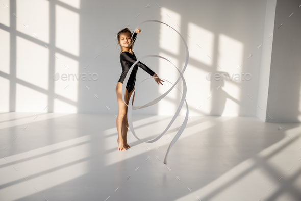 Little girl practising rhythmic gymnastics with a tape
