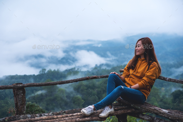 Kan ikke lide Bug Et kors a female traveler sitting and looking at a beautiful mountain and nature  view on foggy day Stock Photo by Farknot