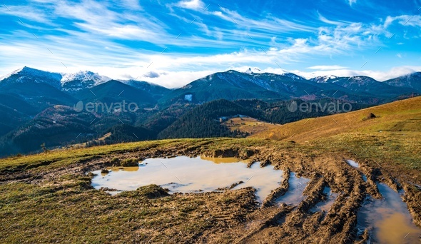 A huge puddle of mud on a path in the Carpathian mountains against the backdrop of beautiful hills