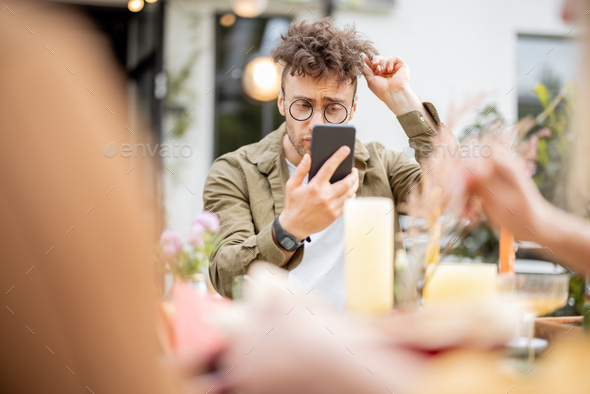 Self lover guy looking at himself on phone while dining with friends outdoors