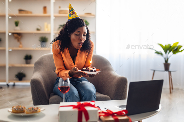 Black Female Blowing Candle On Cake Having Online Birthday Indoor