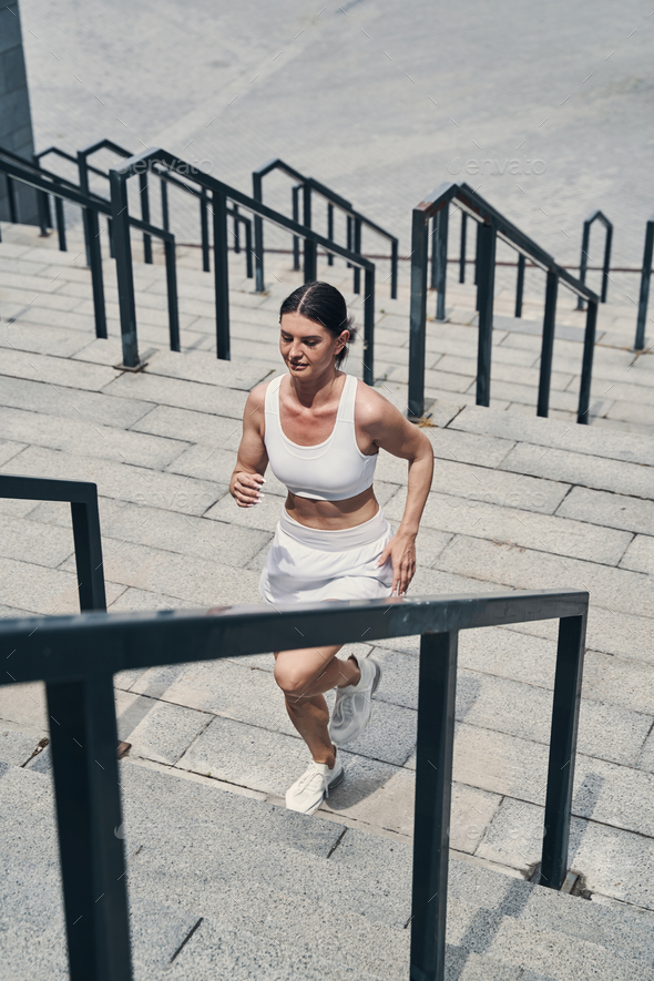 Running sportswoman passing flight of stairs outside Stock Photo