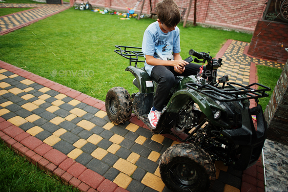 Boy in four-wheller ATV quad bike with mobile phone. - Stock Photo - Images