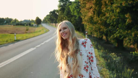 Young Woman Hitchhiking on Countryside Road. alt