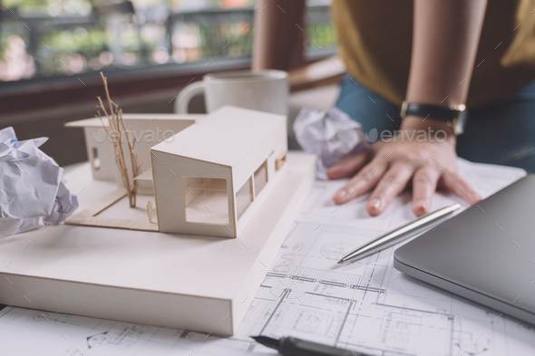 a stressed architects with drawing shop drawing paper with architecture model
