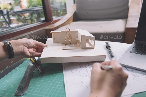 Closeup image of architects drawing shop drawing paper with architecture model on table
