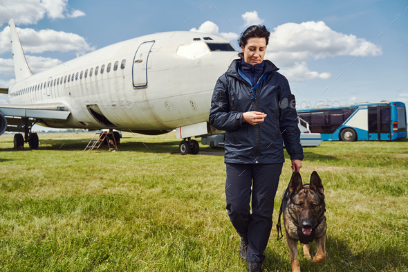 Female security officer with dog walking down airfield