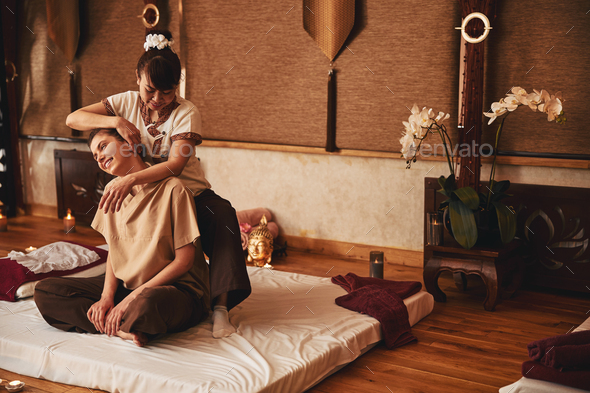 Thai massagist moving her palm along customer ear