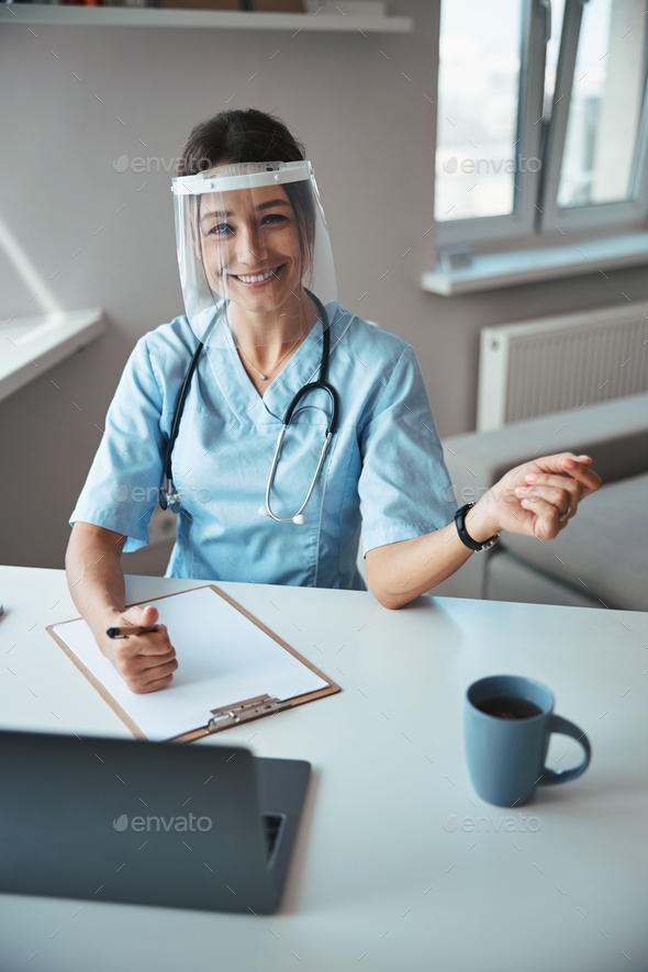 Cheerful female doctor in face mask working in clinic