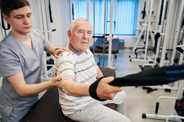 Confident senior citizen doing arm exercise on rehabilitation equipment