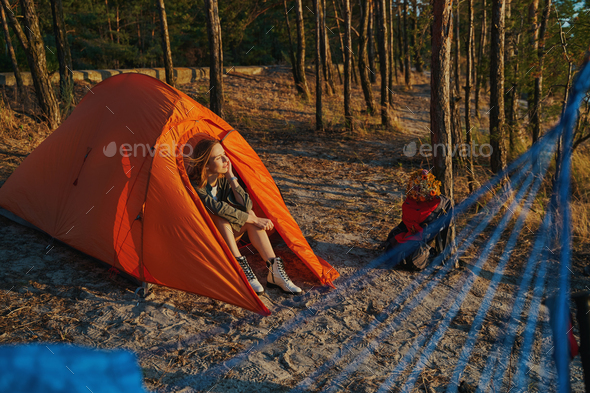 Woman resting in tent while watching sunset