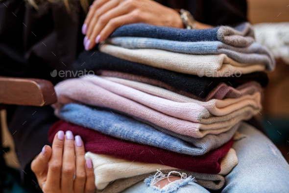 A very large assortment of hats in female hands. Fashion concept, stylist, knitted clothes.