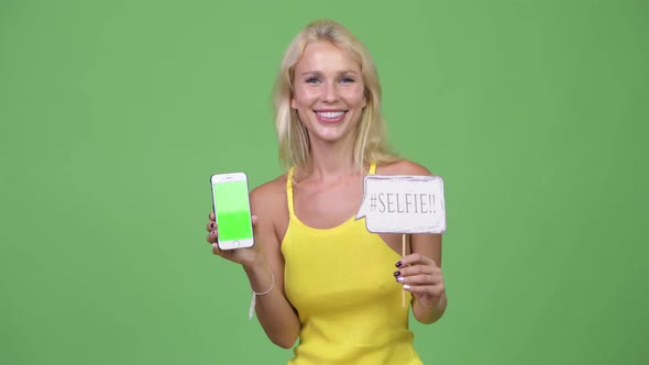 Young Happy Beautiful Blonde Woman Showing Phone with Paper Sign