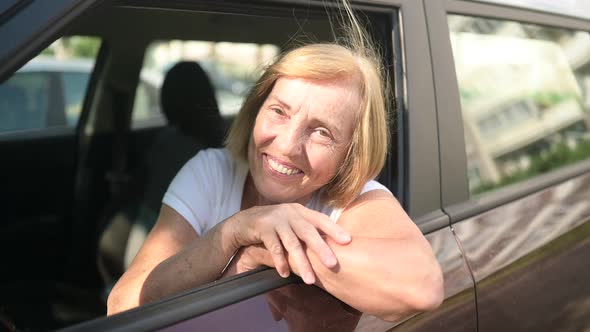 Happy Senior Woman Driving Sitting in New Brown Car Smiling Looking at Camera Enjoying Journey