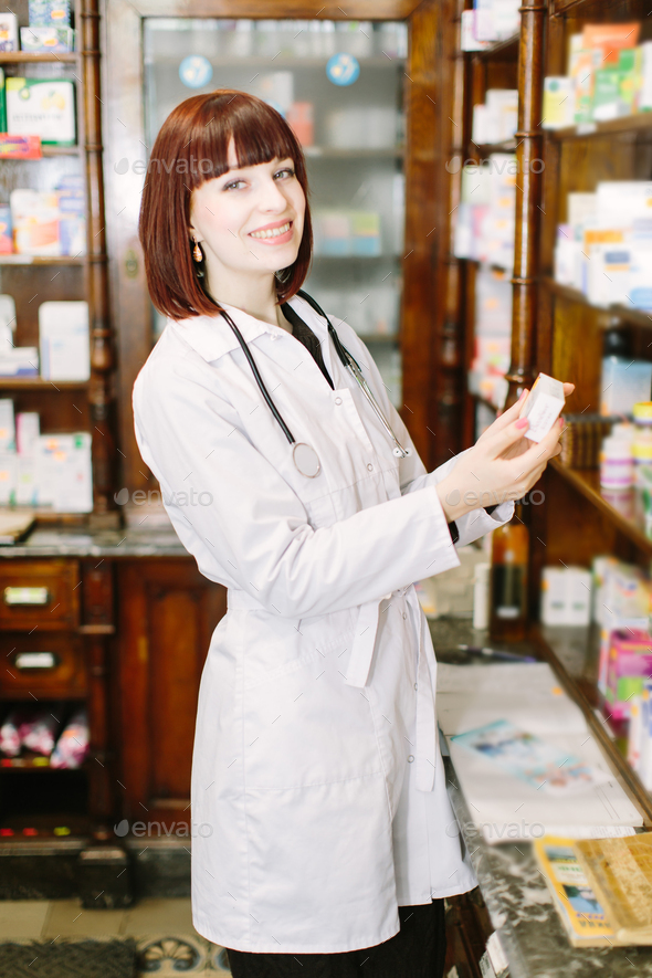 Beautiful darkhaired lady pharmacist choosing the product in drugstore