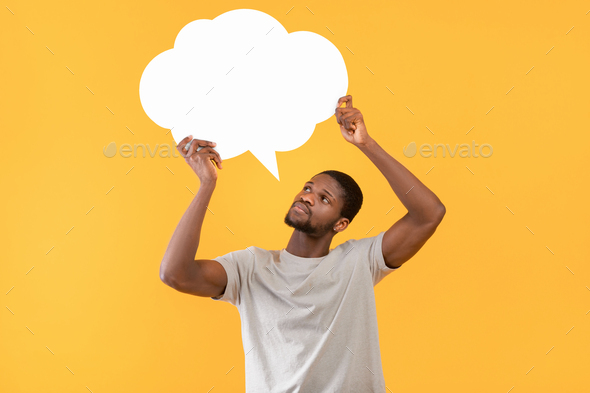 Thoughtful black man holding empty speech bubble over yellow studio background, free space for your