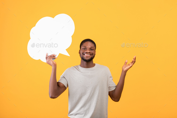 Smiling black man holding blank speech bubble above his head over yellow background, mockup for your