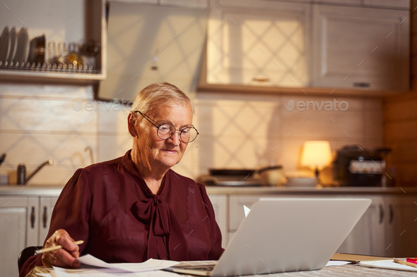 Senior citizen in glasses working at laptop