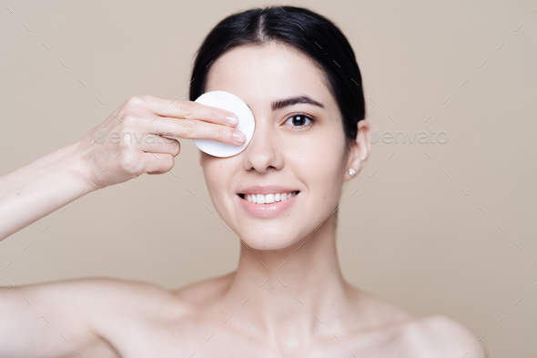 Young brunette woman removing makeup from her face Stock Photo by diignat