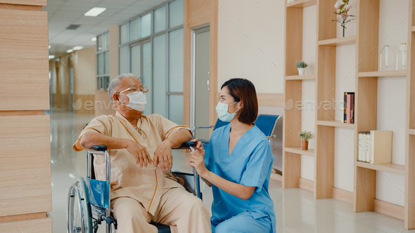 Young Asian woman nurse caregiver wear medical face mask encourage take care her patient explain. - Stock Photo - Images