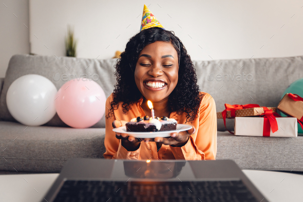 Black Woman Holding Birthday Cake In Front Of Laptop Indoor