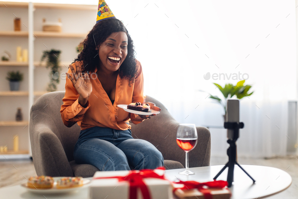 Black Woman Waving Hello To Smartphone Holding Birthday Cake Indoor