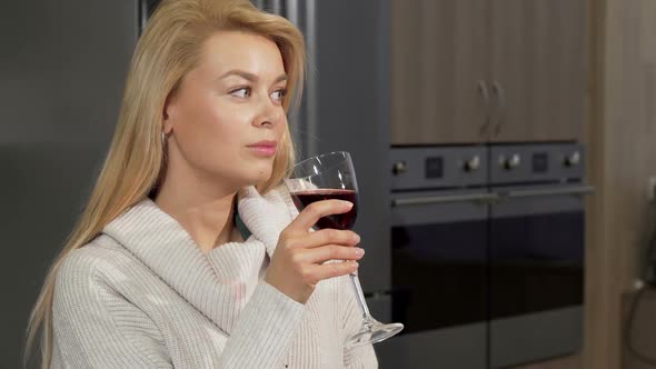 Gorgeous Woman Enjoying Drinking Red Wine at Home at the Kitchen alt