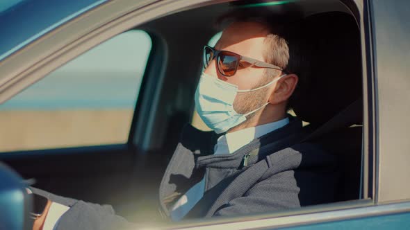 Driver Protective Face Mask In Car. Businessman In Sunglasses Drive Vehicle. Self Isolation On Car. alt