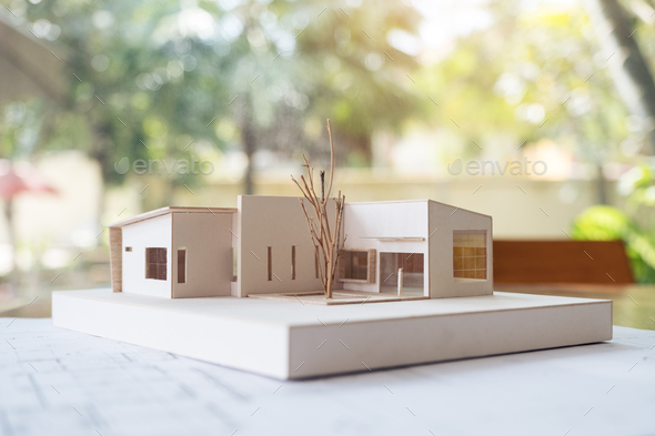 An architecture model with shop drawing paper and laptop on table in office with blur nature