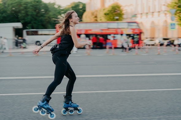 Active slim young woman enjoys rollerskating during spare time