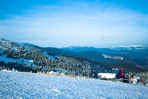 Artificial snow making machine in the Alps. The green artificial snow gun  is against a deep blue sky Stock Photo