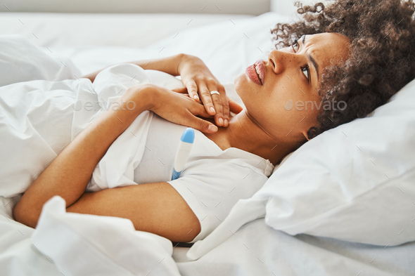 Bedridden African American woman taking her underarm temperature